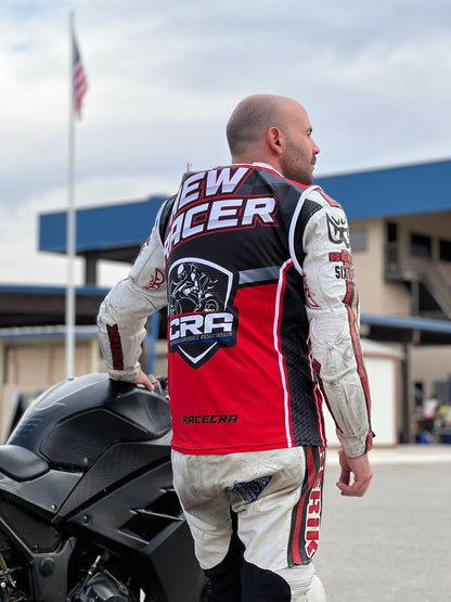 Man in racing gear standing next to a motorcycle with visible branding.