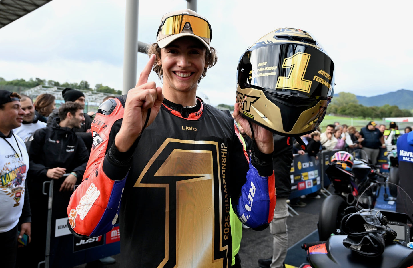 Person in racing gear with helmet and number 1 shirt at a race track event