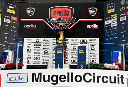 Person on a podium with Aprilia branding at Mugello Circuit